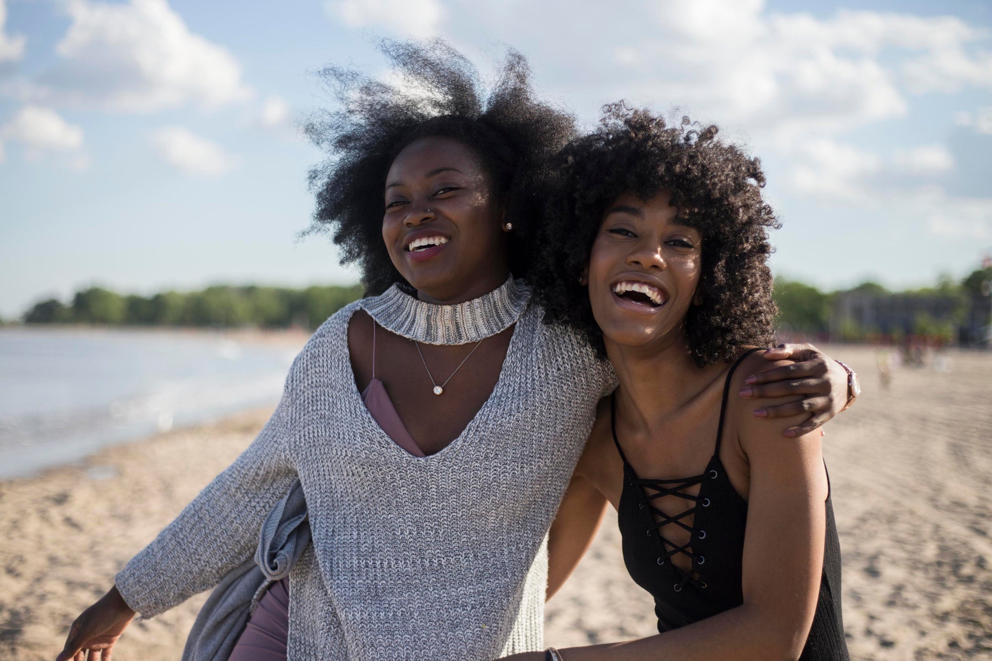 Two women with natural Afro 4c hair hugging each other and laughing on a beach | Lava Cap microwavable heat cap for hair 